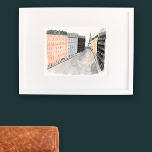 May include: A watercolor illustration of a Parisian street scene with buildings on either side of a cobblestone street. The Eiffel Tower is visible in the distance.