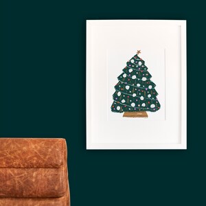 May include: A white framed print of a green Christmas tree with white and colorful ornaments. The tree is decorated with a star on top and a brown base.