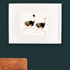 May include: A white framed print of two black and gold ostriches running. The ostrich on the left is wearing a top hat. The ostrich on the right is wearing a white veil.