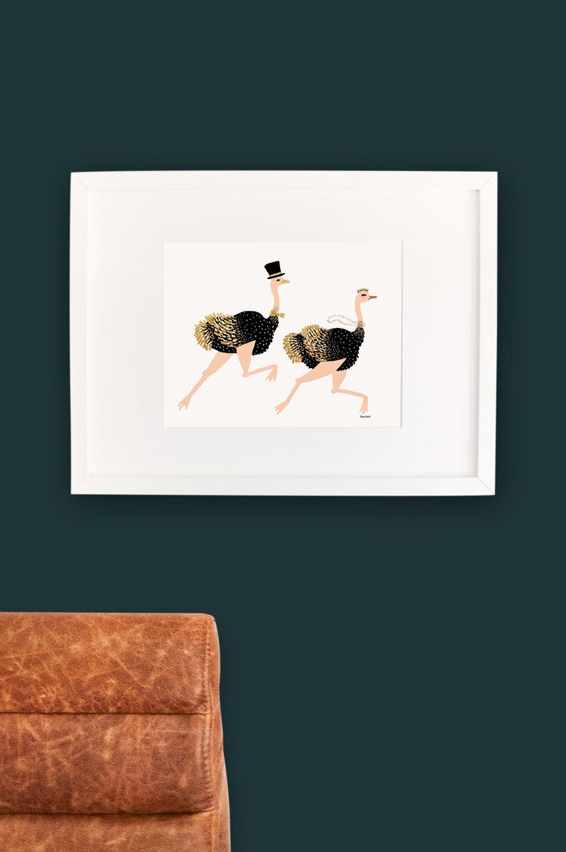 May include: A white framed print of two black and gold ostriches running. The ostrich on the left is wearing a top hat. The ostrich on the right is wearing a white veil.