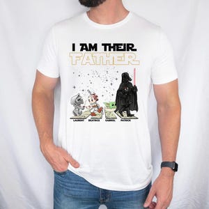 May include: White t-shirt with the text "I AM THEIR FATHER" in black and gold. The shirt features cartoon illustrations of Star Wars characters: Laurent, Beatrice, Gabriel, and Patrick. The names are printed below each character.