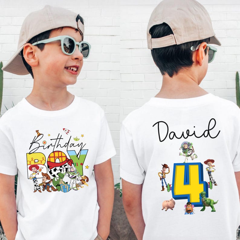 Pode incluir: Camiseta branca com um gr&aacute;fico colorido "Birthday BOY" com personagens de desenhos animados. A parte de tr&aacute;s da camisa tem o nome "David" e o n&uacute;mero "4" com mais personagens de desenhos animados. A camisa &eacute; usada por uma crian&ccedil;a.