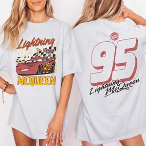 Puede incluir: Camiseta azul claro con Lightning McQueen de la pel&iacute;cula Cars. El dise&ntilde;o frontal muestra a McQueen, el n&uacute;mero 95 y el nombre "McQueen". La parte trasera muestra un gran n&uacute;mero 95 y "Lightning McQueen".