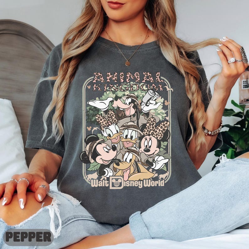 May include: Dark grey t-shirt with a graphic of Disney characters, including Mickey and Minnie Mouse, Donald and Daisy Duck, and Goofy. The shirt has the words "ANIMAL KINGDOM" and "Walt Disney World" printed on it.