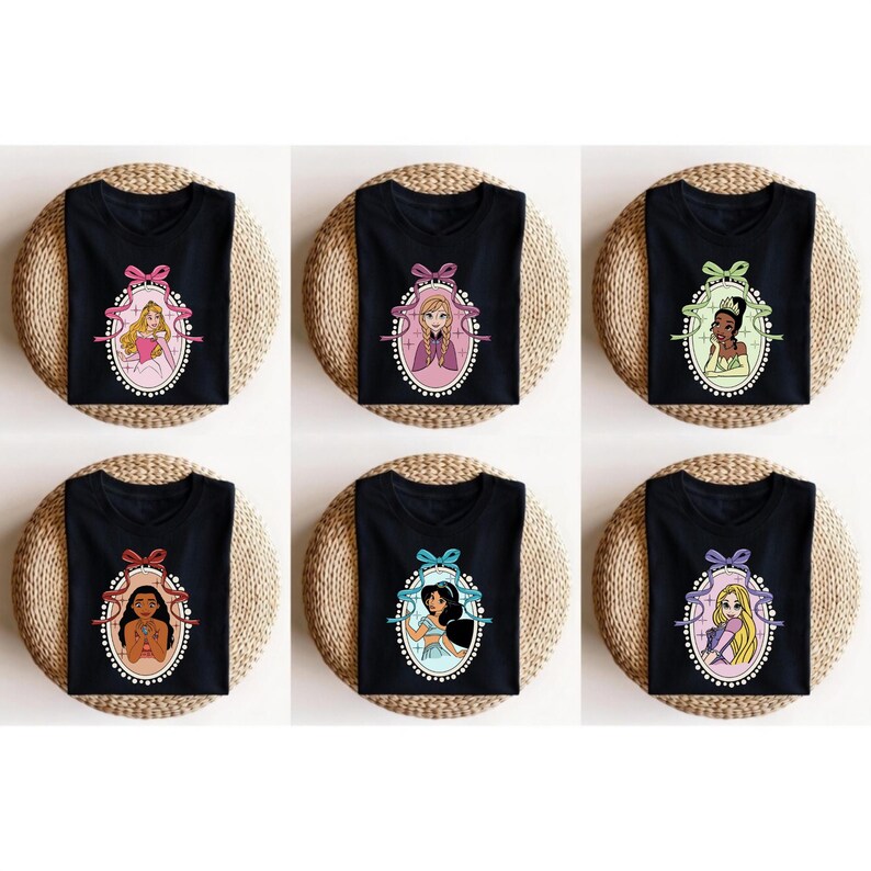 K&ouml;nnte beinhalten: Schwarze T-Shirts mit Prinzessinnenportr&auml;ts in ovalen Rahmen und Schleifen. Jedes Shirt zeigt eine andere Prinzessin, darunter Aurora, Rapunzel, Tiana, Pocahontas, Jasmin und Anna. Die Shirts werden auf gewebten Matten pr&auml;sentiert.