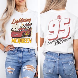 Puede incluir: Camiseta blanca con un dise&ntilde;o de Rayo McQueen de la pel&iacute;cula Cars. El dise&ntilde;o frontal incluye el texto "Lightning 95 McQueen" con una bandera a cuadros. La parte trasera muestra un gran "95" y el texto "Lightning McQueen".
