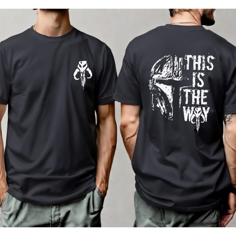 May include: A dark gray short-sleeved t-shirt featuring a white graphic of a helmeted skull on the left chest. The back of the shirt displays a large white graphic of a helmet and the text THIS IS THE WAY in a distressed, bold font style.
