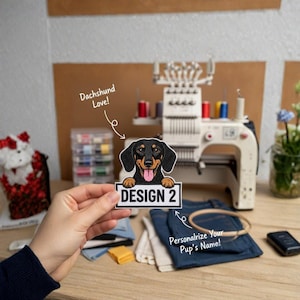 Può includere: Una toppa di bassotto nero e marrone con la scritta "DESIGN 2" su sfondo bianco. La toppa è tenuta davanti a una macchina da ricamo e tessuto denim. L'immagine include anche il testo "Dachshund Love!" e "Personalize Your Pup's Name!"