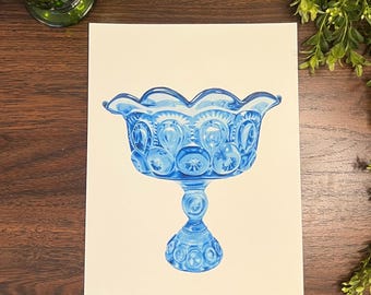 May include: A blue glass pedestal bowl with a scalloped rim. The bowl features a star and moon pattern and sits on a detailed pedestal base. The bowl is a decorative piece, likely for serving or display.