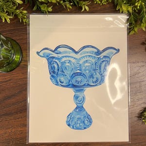 K&ouml;nnte beinhalten: Illustration einer blauen Glas-Fu&szlig;schale. Die Schale hat einen gewellten Rand und ein sich wiederholendes Muster aus Sternen und Kreisen. Das Kunstwerk befindet sich auf wei&szlig;em Hintergrund und ist in einer transparenten Kunststoffh&uuml;lle gesch&uuml;tzt.