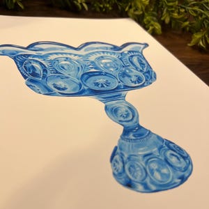 K&ouml;nnte beinhalten: Eine blaue Glas-Kompottschale mit gewelltem Rand und komplizierten Stern- und Kreismustern. Der Stiel ist mit &auml;hnlichen Designs versehen. Das Kunstwerk ist ein Aquarell auf wei&szlig;em Papier, das antike Glaswaren zeigt.