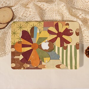 May include: A rectangular laptop skin featuring a collage of retro-inspired floral shapes in shades of mustard yellow, olive green, and deep maroon. The design includes geometric patterns, grid lines, and a central white Apple logo cutout.