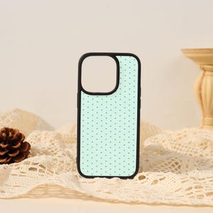 May include: A rectangular phone case featuring a light mint green background with a repeating pattern of small, dark teal polka dots. The case has a solid black border and a large square cutout in the upper left corner for the camera lens assembly.