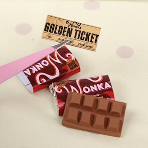 Pode incluir: Miniaturas de barras de chocolate e embalagens com a palavra "WONKA" em escrita branca sobre um fundo vermelho e castanho. Também está presente um "GOLDEN TICKET", com o texto "FEB. 1" e "FRONT GATES".
