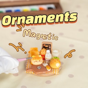 May include: A selection of miniature, magnetic food-themed ornaments. The ornaments include a cat-shaped bread, a small pineapple, and a tiny carton of milk. The word "Ornaments" is displayed in a yellow and orange font.