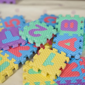 May include: Colorful foam puzzle pieces with numbers and letters. The pieces are in various colors, including blue, green, yellow, purple, and red. The numbers and letters are in contrasting colors, making them easy to identify. Educational toy.
