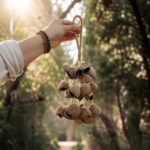 Peut inclure: Un ornement décoratif suspendu composé de nombreuses moitiés de coquilles de noix brunes et texturées, fixées à une boucle centrale en corde de jute. Les coquilles sont regroupées et attachées par de fines ficelles, créant un aspect naturel.