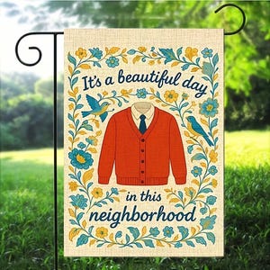 Puede incluir: Una bandera de jardín con el texto "It's a beautiful day in this neighborhood". La bandera presenta una rebeca naranja, una camisa blanca con cuello y una corbata azul. Los pájaros azules y los diseños florales en azul y amarillo rodean el texto y la imagen central.