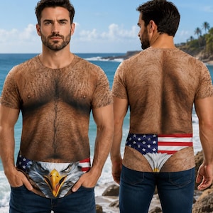 Puede incluir: Una camiseta de manga corta con un estampado realista de un pecho y torso velludos. La parte delantera muestra un gráfico de la cara de un águila calva con la bandera estadounidense, mientras que la parte trasera muestra la bandera.