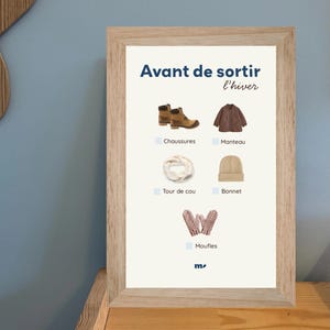 May include: A framed print with the text "Avant de sortir l'hiver" and illustrations of winter clothing. Includes boots, a coat, a scarf, a beanie, and mittens. The items are in shades of brown, beige, and pink.