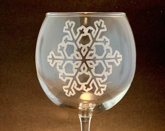 May include: A clear glass wine glass with a snowflake etched into the side.
