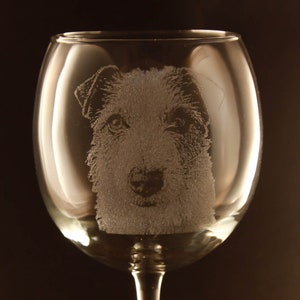 May include: A clear glass wine glass with an etched image of a dog's face.