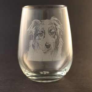 May include: A clear glass wine glass with an etched image of a dog's face. The glass has a paw print at the bottom.