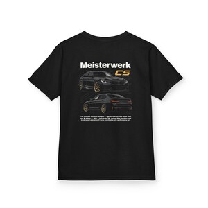 May include: Black t-shirt featuring a graphic of two black cars with gold rims. The text "Meisterwerk CS" is above the car illustrations. The shirt also has text at the bottom that reads "The ultimate four-door weapon..."