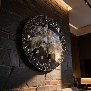 Könnte beinhalten: Eine runde Wanduhr mit einem schwarz-gold marmorierten Zentrum und einem strukturierten Rand aus dunklen, reflektierenden Glassplittern. Das Zifferblatt zeigt weiße römische Ziffern und dünne schwarze Zeiger in einem kontrastreichen Design.