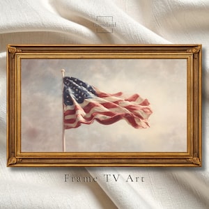 Puede incluir: Impresión enmarcada con la bandera estadounidense ondeando al viento contra un cielo nublado. La bandera muestra rayas rojas y blancas y un campo azul con estrellas blancas. El marco es dorado y el texto "Frame TV Art" está en la parte inferior.