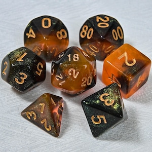 May include: A set of seven polyhedral dice in various shapes. The dice are a mix of black, orange, and gold, with gold numbering. The set includes a D4, D6, D8, D10, D12, D20, and a percentile die.