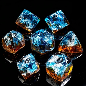 Può includere: Un set di sette dadi poliedrici caratterizzati da un design bicolore con una base color ambra traslucida e una sezione superiore blu vibrante con riflessi metallici. Ogni dado presenta numeri neri incisi sulle sue facce geometriche.