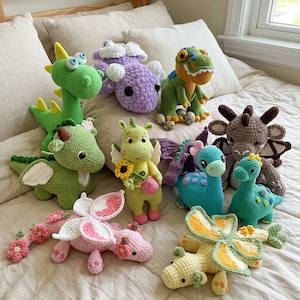 Könnte beinhalten: Eine Sammlung von zehn gehäkelten Stofftieren in verschiedenen Formen und Farben, darunter grüne, violette, rosa, gelbe und blaue Drachen und Dinosaurier. Die Figuren weisen detaillierte Maschen, Flügel, Hörner und florale Akzente auf.
