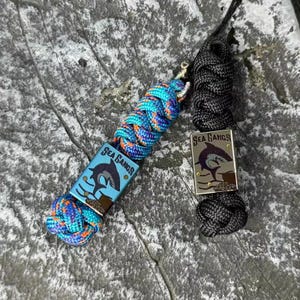 May include: Two keychains with the text "Sea Gangs". One is black, the other is blue, orange, and purple. Each keychain has a metal tag with a shark illustration.