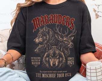 May include: A black t-shirt featuring a graphic print with the text "MARAUDERS" in red, "THE MARAUDERS: MASTERS OF MAYHEM", "SINCE 1971", and "THE MISCHIEF TOUR 1978". The design includes detailed illustrations of a wolf, a stag, and a rat.