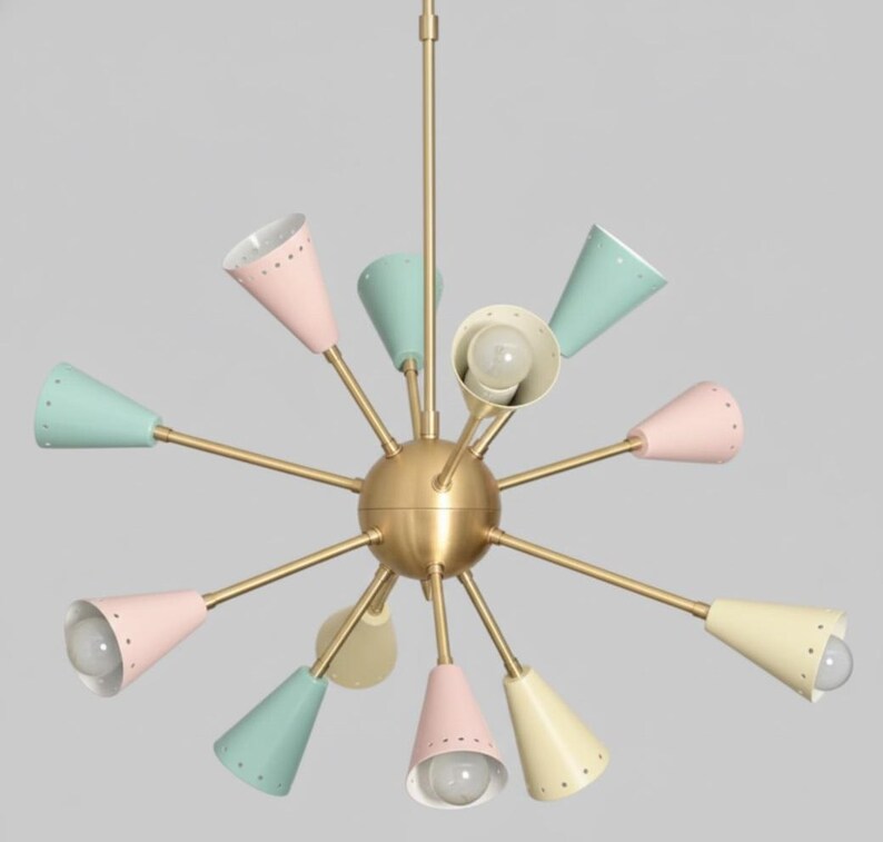 Puede incluir: Una l&aacute;mpara de ara&ntilde;a de estilo retro con una esfera central de lat&oacute;n y m&uacute;ltiples brazos. Cada brazo sostiene una pantalla c&oacute;nica en tonos pastel, rosa, verde menta y amarillo. Las l&aacute;mparas tienen peque&ntilde;os agujeros en el borde.