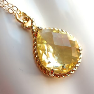 May include: A gold necklace with a teardrop-shaped yellow gemstone pendant.