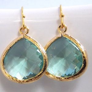 May include: A pair of gold teardrop earrings with light blue crystal stones.