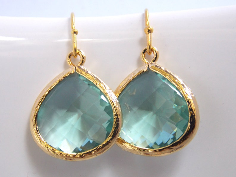 May include: A pair of gold teardrop earrings with light blue crystal stones.