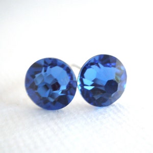 May include: A pair of blue stud earrings with a round, faceted design.