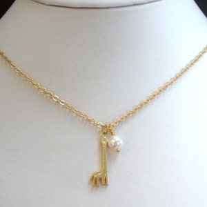 Pode incluir: Um colar de corrente de ouro com um pequeno pingente de girafa de ouro e uma p&eacute;rola branca pendurada no pingente.