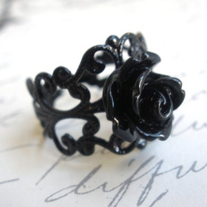 May include: A black filigree ring with a black rose design.