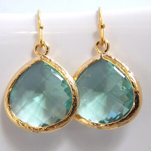 May include: A pair of gold teardrop earrings with light blue crystal stones.
