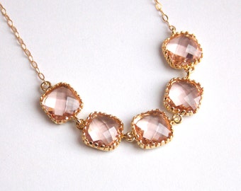 May include: A delicate gold chain necklace with five pink faceted square-shaped stones set in gold.