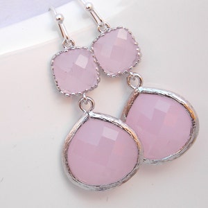 May include: A pair of silver dangle earrings with pink faceted glass stones. The earrings have a square stone at the top and a teardrop-shaped stone at the bottom.