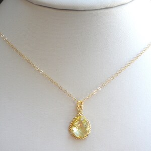 May include: A gold chain necklace with a teardrop-shaped pendant featuring a yellow gemstone.