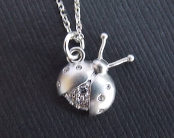 Puede incluir: Collar de plata con un colgante de mariquita con detalles de cristal transparente.
