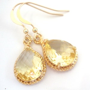 May include: Gold teardrop earrings with a yellow gemstone. The earrings have a twisted rope design around the gemstone.