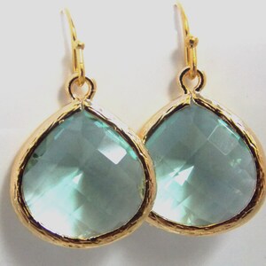 May include: A pair of gold teardrop earrings with light blue crystal stones.