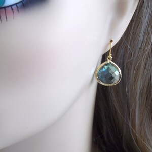 May include: Gold teardrop earrings with a blue-green gemstone.